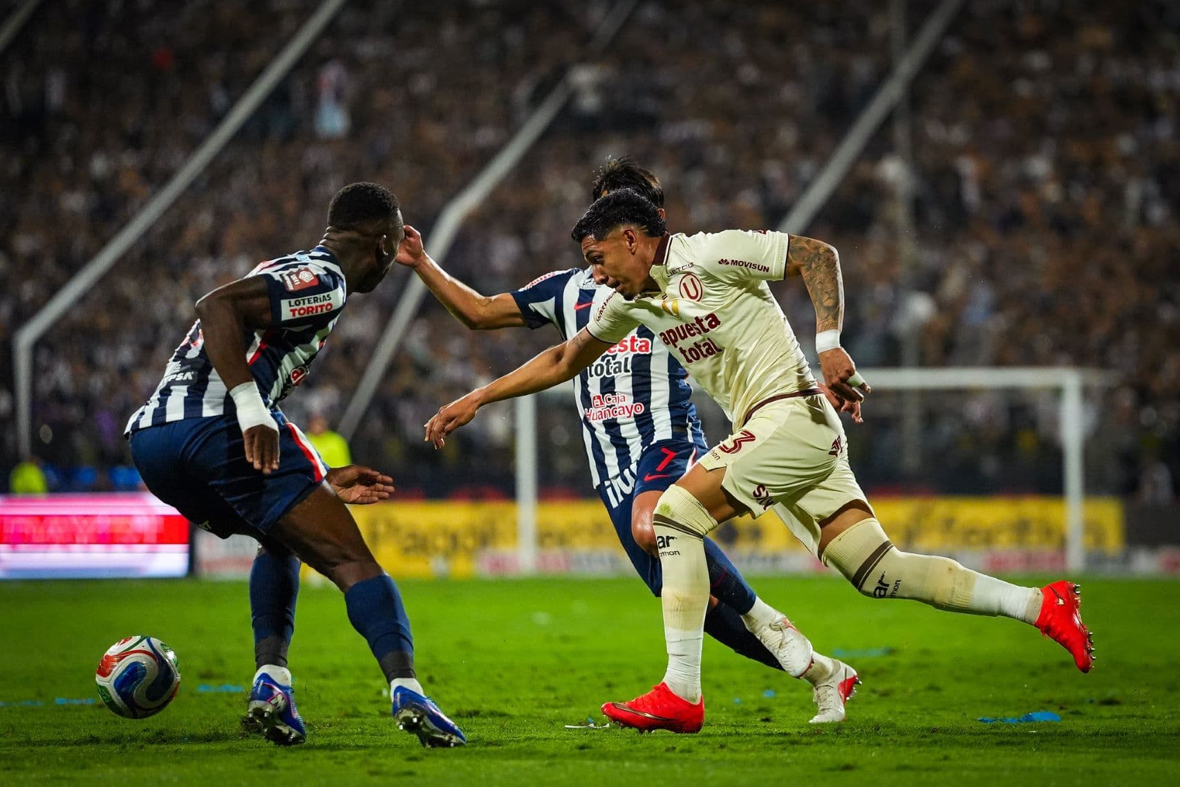 César Inga pasa entre dos jugadores rivales
